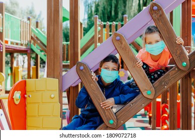 Children Wearing Protective Masks Playing On Playground   