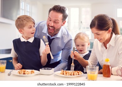 Children Wearing School Uniform In Kitchen Eating Breakfast Waffles As Parents Get Ready For Work