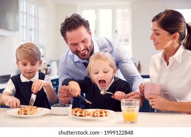 Children Wearing School Uniform In Kitchen Eating Breakfast Waffles As Parents Get Ready For Work