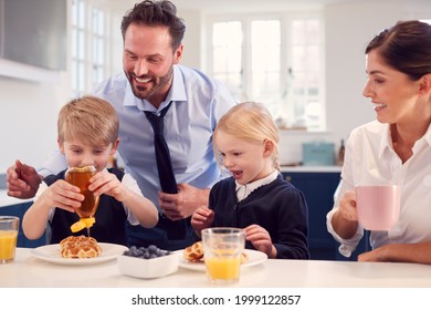 Children Wearing School Uniform In Kitchen Eating Breakfast Waffles As Parents Get Ready For Work