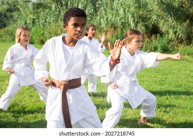 Children in white kimono practicing karate in summer outdoors