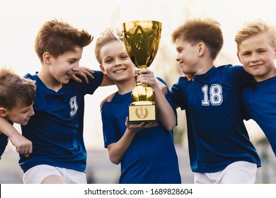 Children Winning Soccer Tournament. Group Of Happy Boys Holding Golden Trophy. School Sports Team Celebrating Success. Overjoyed Kids In Football Sports Team