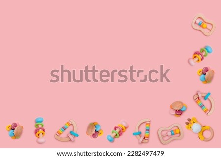 Children wooden rattles for baby on pink background. Eco-friendly toys for newborns in the colors of the rainbow. Flat lay, copy space.