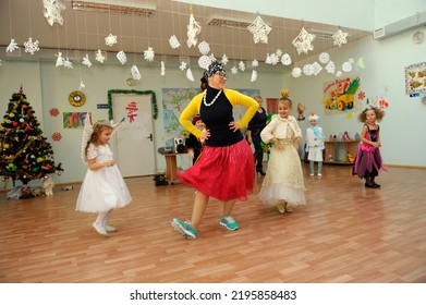 Children And Young Cheerful Woman Host In Carnival Costumes Dancing During New Year Eve Party In The Kindergarten. December 29, 2013. Kyiv, Ukraine