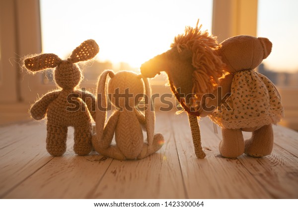 Children\'s animal stuffed toys bunny and teddy\
family on wooden floor in kids\
room.
