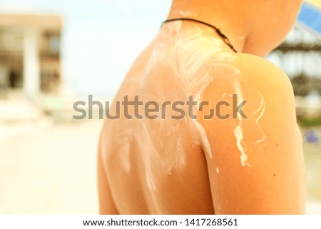 Anonymous woman applying sunscreen by the poolside