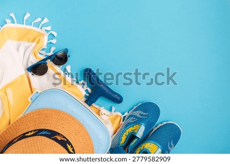 Children's beach essentials including a hat, sunglasses, water shoes, suitcase, and towel.  Travel flat lay
