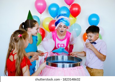 Children's birthday party. Teenagers in caps and a fairy woman make candy floss.