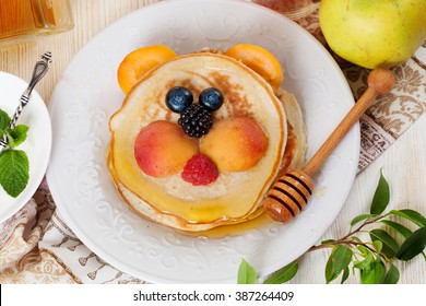 Children's breakfast pancakes smiling face of the sun lion strawberry blueberry and apricot, cute food, honey, creative idea