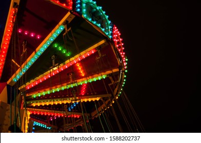 Children's Carousel At An Amusement Park In The Evening And Night Illumination. Amusement Park At Night.