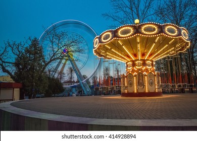 Children's Carousel At An Amusement Park In The Evening And Night Illumination