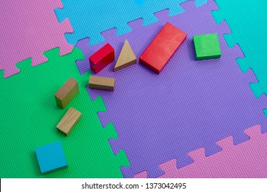 Children's Colourful Toy Woodern Bricks Laid Out On A Multi Coloured Childs Play Mat.