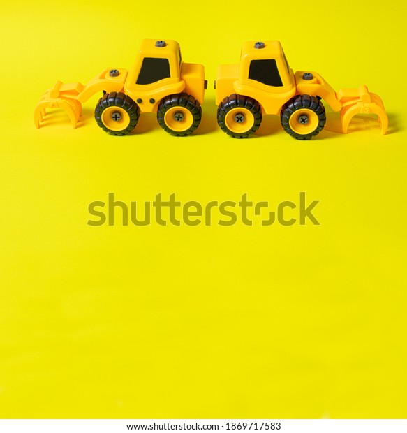 Children\'s construction\
machine log loader on a yellow background - two toys. Tractor for\
the boy and banner for the toy store with a place for text copy\
space square photo