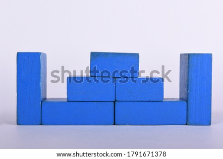 Children's creativity in the form of buildings structures and houses made of wooden geometric shapes in blue on a white background