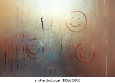 Children's Drawing Of A Smile On The Window. A Smiling Face Painted On A Fogged Window.Draw A Face On The Fogged Glass With Your Finger