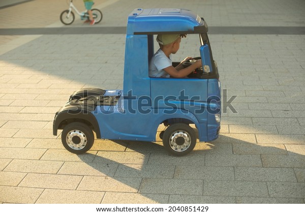 Children\'s electric car. A small truck for a\
child. A blue car driven by a\
preschooler.