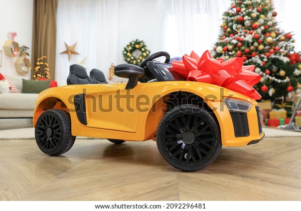 Children\'s electric toy car with red bow in\
room decorated for\
Christmas