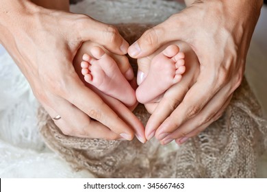 Children's feet in hands of mother and father.  Mother, father and Child. Happy Family concept. Beautiful conceptual image of Motherhood
