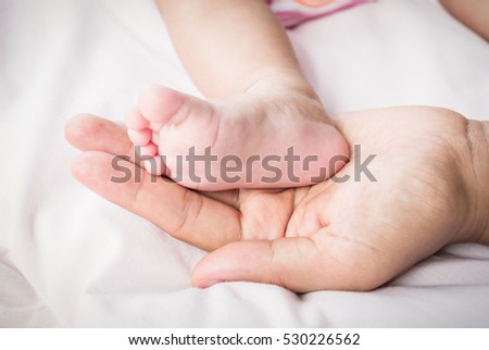 Children's feet with his mother's hands