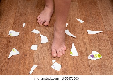 Children's Feet Are On The Floor Around The Broken Plate. The Child Broke The Plate.