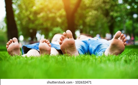 Children's Feet  On Grass. Family Picnic In  Park