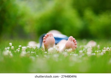 Childrens Feet On Grass Outdoors In Summer Park