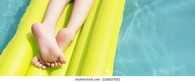 Children's feet, on a yellow inflatable mattress, in the pool, on a sunny summer day. The concept of travel and summer holidays. Banner, space for text - Shutterstock ID 2168107031
