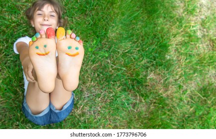 Children's feet with a pattern of paints smile on the green grass. Selective focus. nature. - Powered by Shutterstock