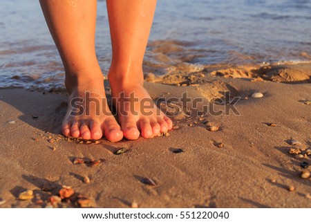 Children's feet in the sand and the sea