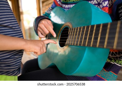 Children's And Female Hands On The Strings Of A Guitar. Learning To Play A Musical Instrument. Mom And Child Spend Time Together. School Of Music