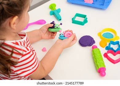 children's games with plasticine, children's hands with plasticine snails, creative games, playing dough, closeup