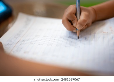 Children's hand book. Child’s hand holding a pencil and writing on lined paper. Student doing homework. Kids handwriting. - Powered by Shutterstock