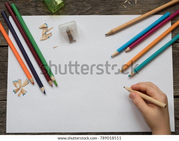 children\'s hand\
with a pencil on a sheet of\
paper