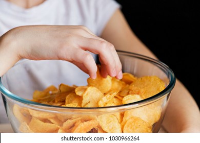 children's hand takes chips out of glass bowls, harmful food.