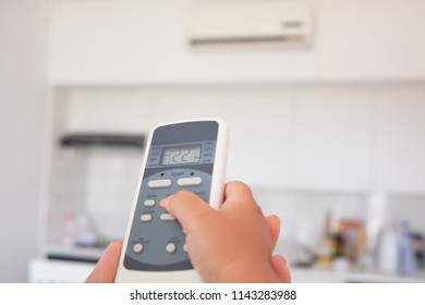 children's hand turns on the air conditioner using the remote control - Shutterstock ID 1143283988