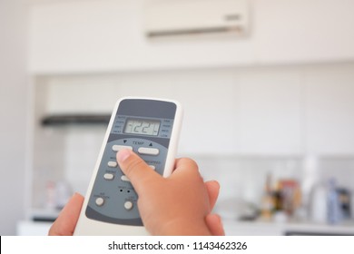 children's hand turns on the air conditioner using the remote control - Shutterstock ID 1143462326