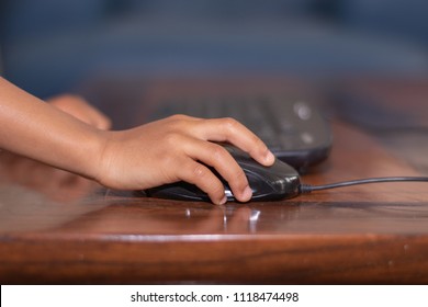 Children's Hand Using a Mouse and Keyboard on a Wooden Table