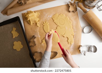 Children's hands cut out a shape for Easter cookies on rolled out dough in a spring decor