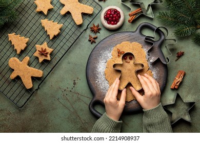 Children's hands cutting shapes and making Christmas cookies. Gingerbread man. Raw batter flavored with ginger, hazelnut, nutmeg, and cinnamon. Christmas and New Year food. Top view of kitchen table.