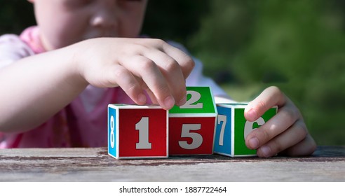Children's Hands Hold Learning Cubes With Numbers. Initial Training In Counting. Foundations Of Mathematics.