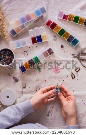Children's hands holding a beaded parrot in the workplace. Top and vertical view