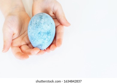Children's hands are holding an Easter egg. Beautiful egg painted for Easter. Close up of a blue egg