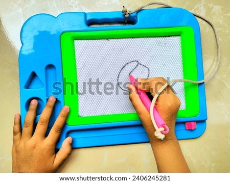 Children's hands are learning to draw using a toy magnetic educational boards made of plastic, this educational board can also be used to learn to write
