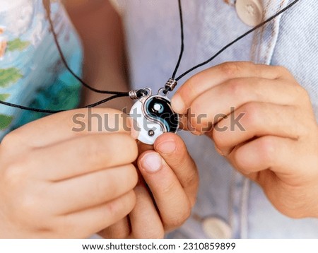 Children's hands linking a yin-yang necklace.