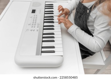 Children's hands on the keys of the synthesizer. Close-up.