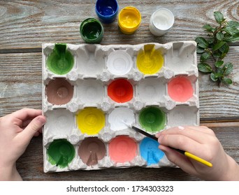 Children's hands paint colored eggs box on a wooden background. - Powered by Shutterstock