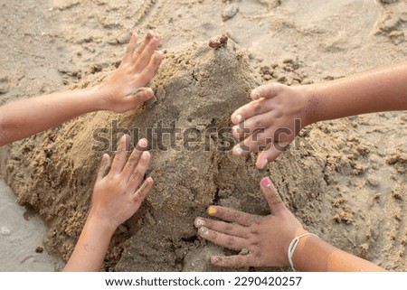 Children's hands are playing and building sand castles on the beach. Happy recreation and holiday activity.