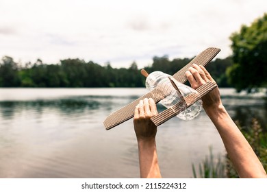children's hands playing with a plane built with recycled material (wood, PVC bottles, cardboard) - Shutterstock ID 2115224312