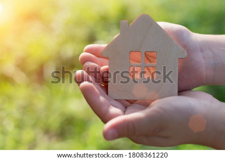 In children's hands a small wooden house. This concept is the dream of every orphaned child to find their own family and home. The picture is horizontal, soft focus, taken on the street