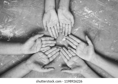 children's hands together in a circle with their hands up on a gray background, top view. joint support and assistance in the community.black and white.